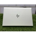 White HP laptop with logo on green grass surface.